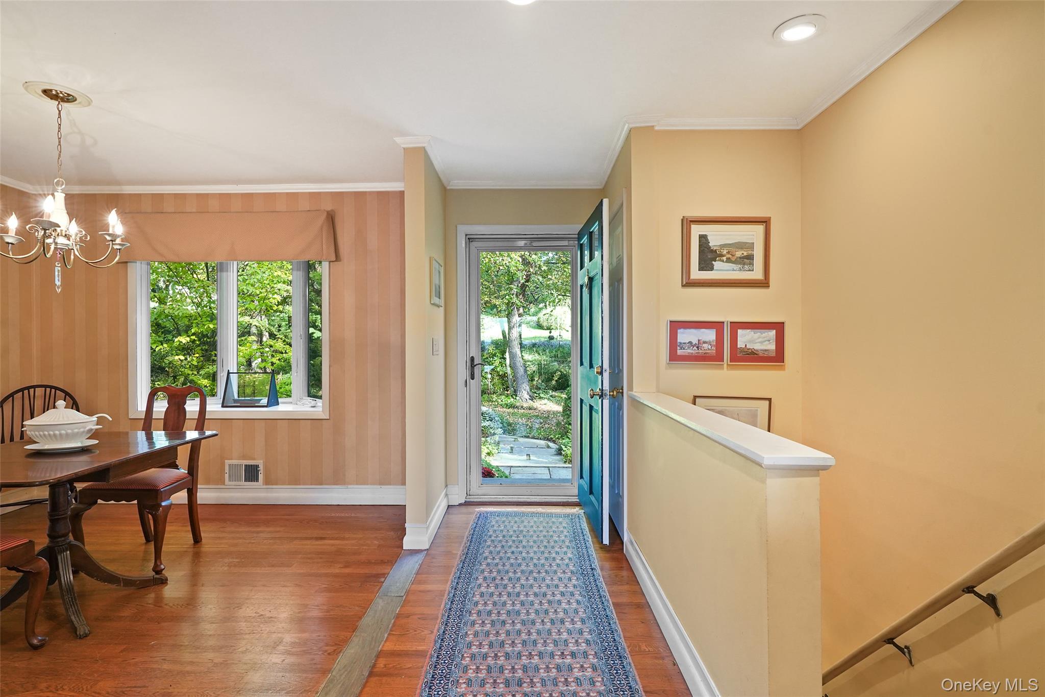 Entry foyer with hardwood floors and a patterned runner beside an open blue front door.