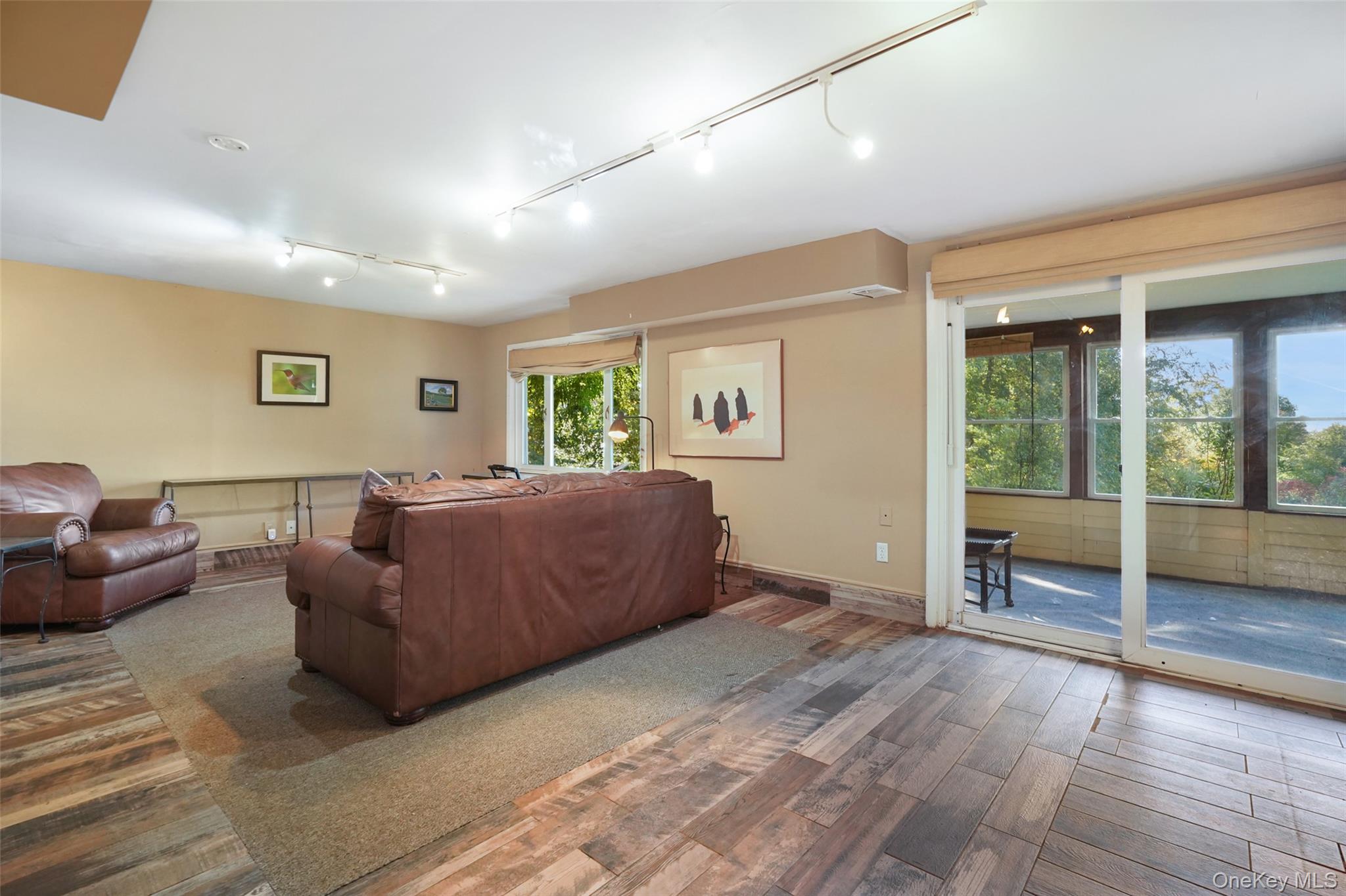 Living room with brown leather sofas and sliding doors to a bright, windowed sunroom.