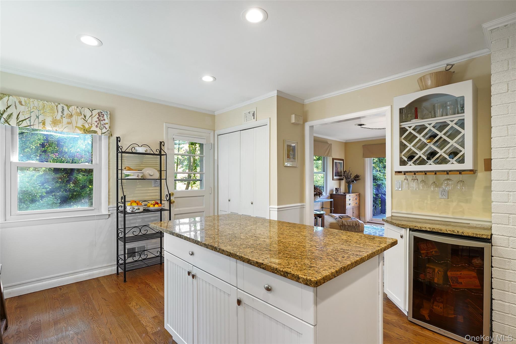 Kitchen with a large granite island, hardwood floors, and built-in wine storage.