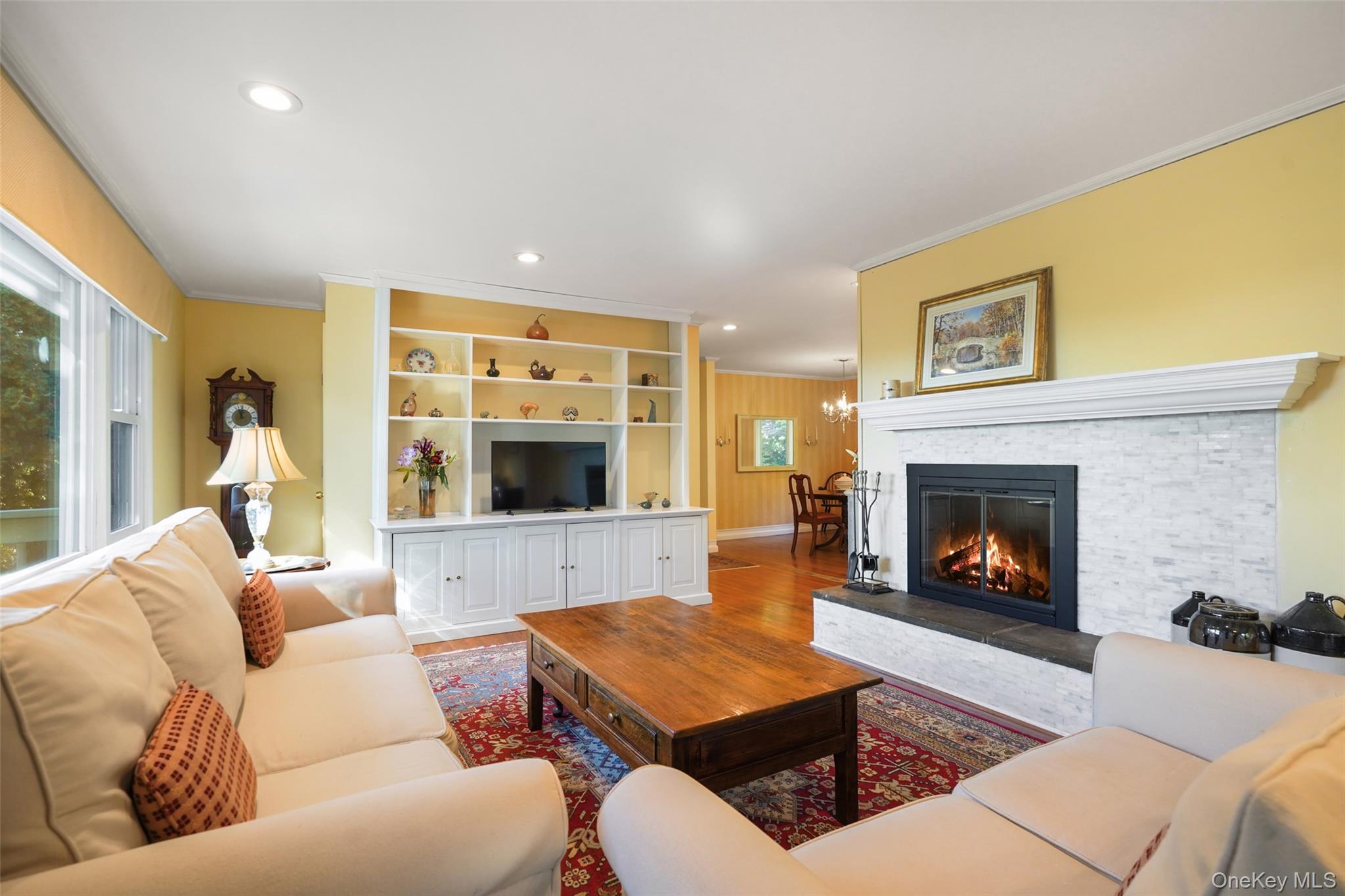 Living room with a lit stone-surround fireplace, built-in shelving, and cream sofas.