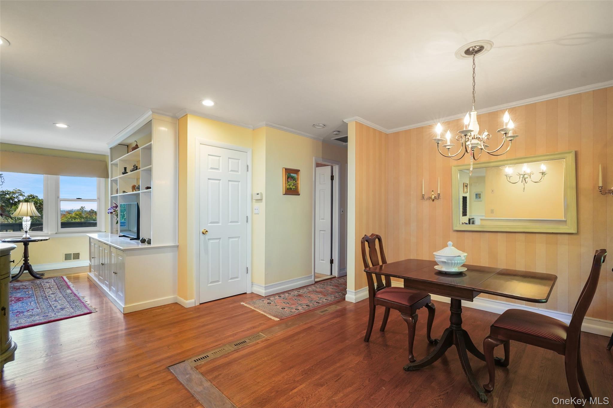 Dining room with a dark wood table, chandelier, striped walls, and a bright adjoining sitting nook.