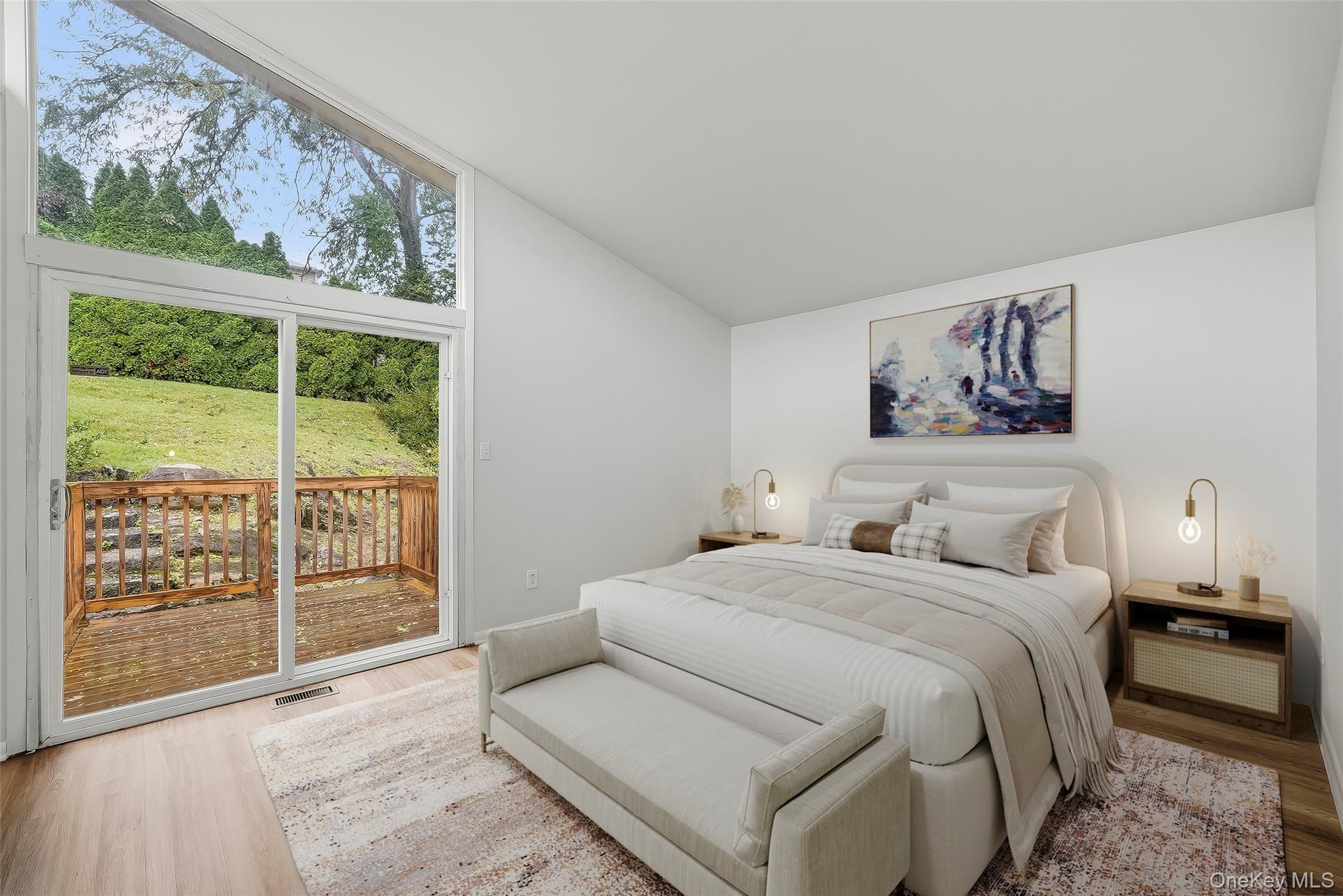 Staged bedroom with a king-size bed and large sliding glass door opening onto a wooden deck.