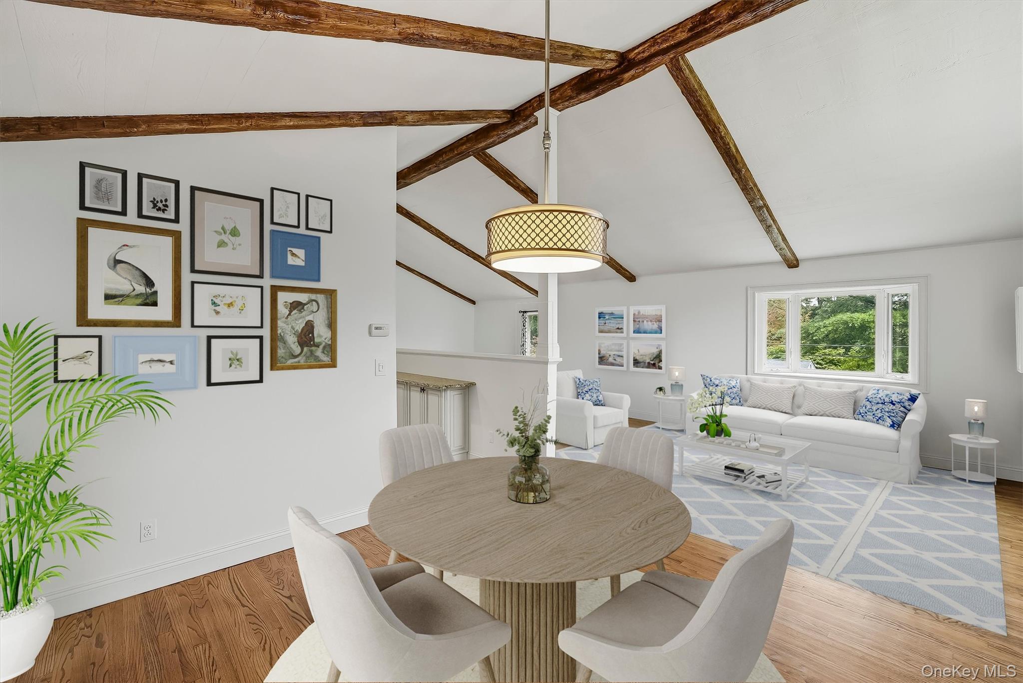 Open-plan living and dining room with exposed beams, white seating, and a round dining table.