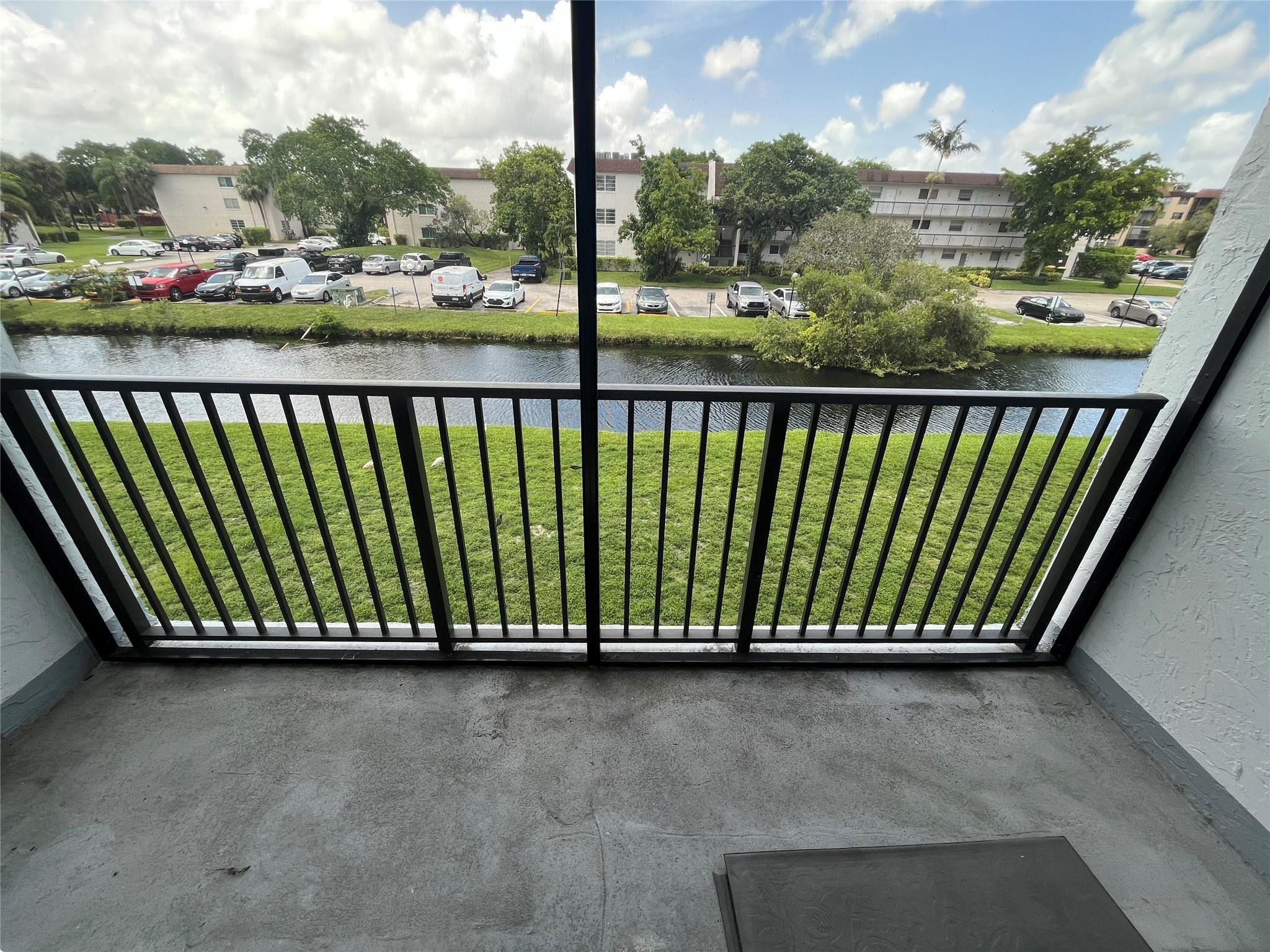 Apartment balcony overlooking a canal, with a black metal railing and neighboring buildings beyond.