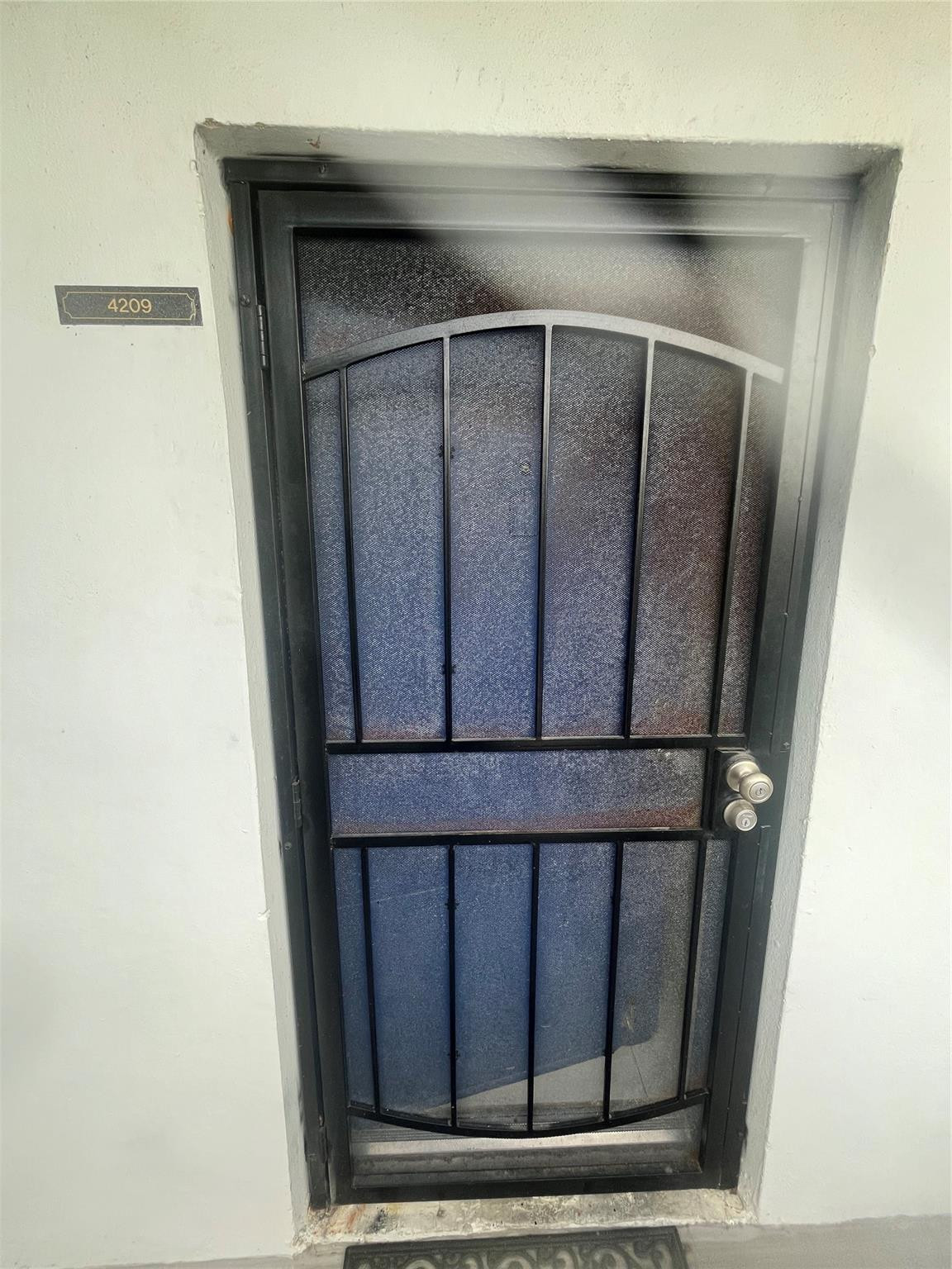 Unit 4209 entrance with a black metal security screen door and number plaque.
