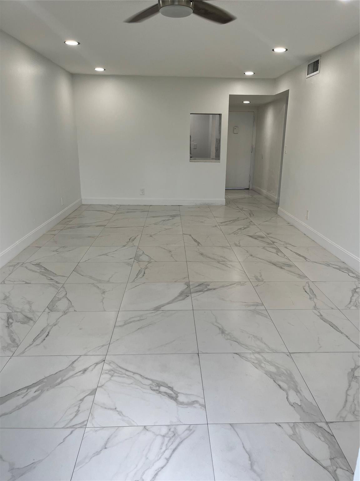 Vacant room with large marble-look tile floors, recessed lights, and a ceiling fan.