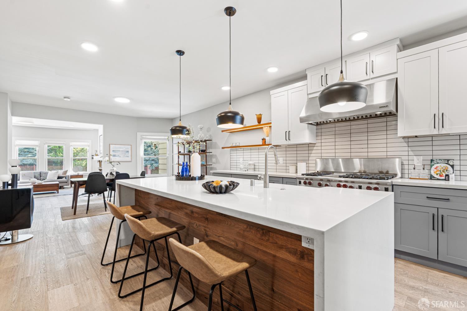 Renovated kitchen with a large white island, walnut paneling, and stainless-steel range opening to the living area.