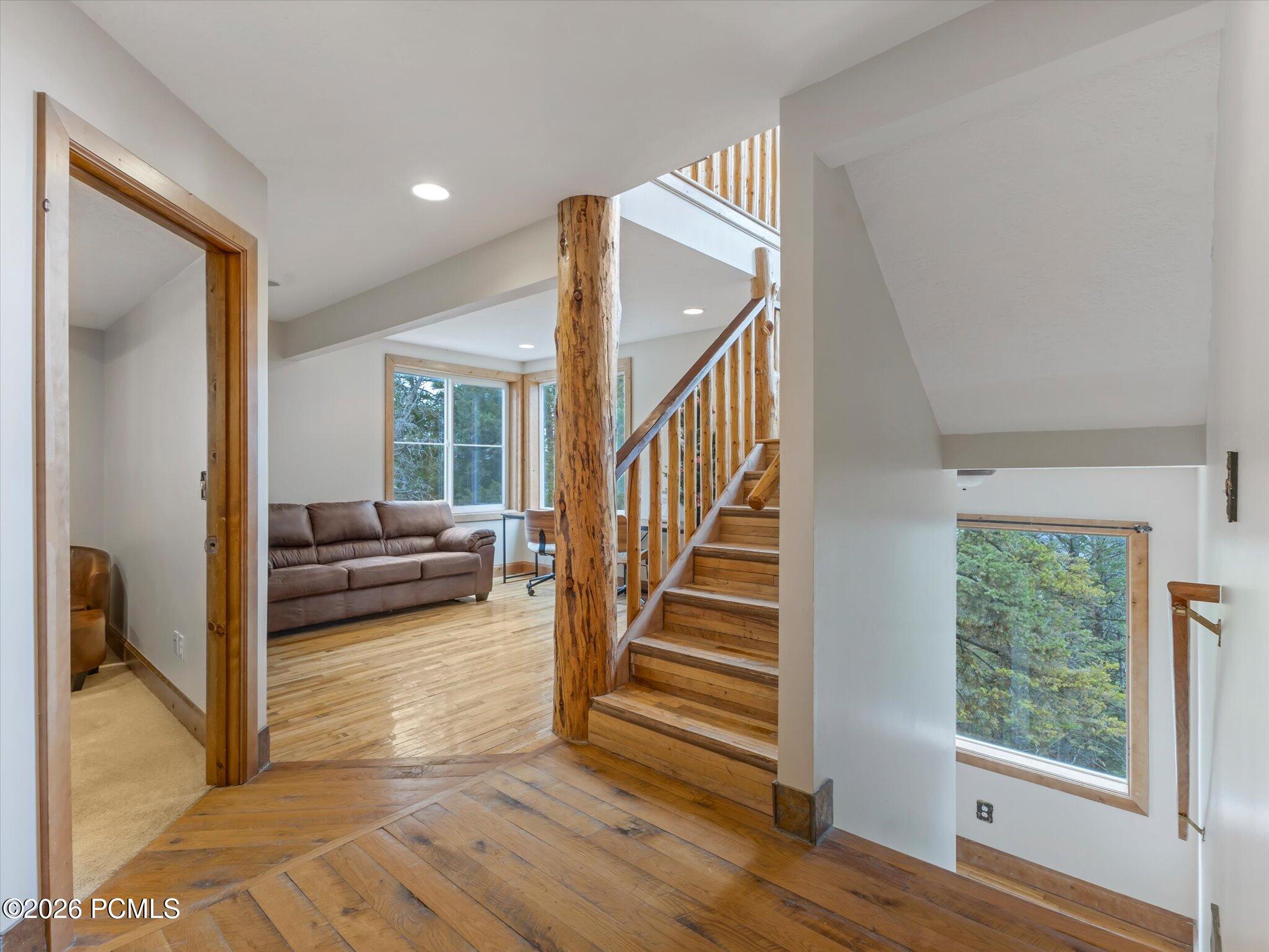Entryway with a wooden staircase, log support post, and living room beyond.