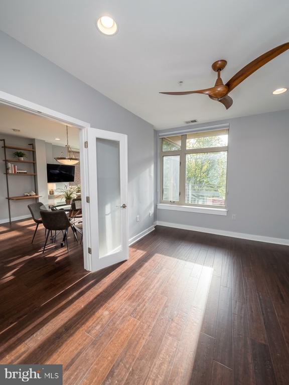 Vacant room with hardwood floors, a large window, and a wood ceiling fan.