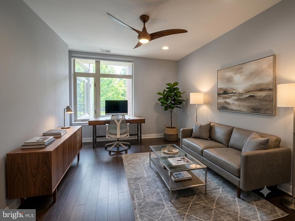 Living room and home office with a gray sofa and desk beside a large window.