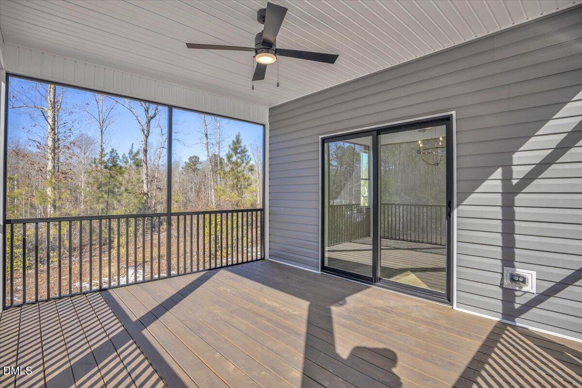 Screened porch with a ceiling fan, sliding glass door, and wooded views.