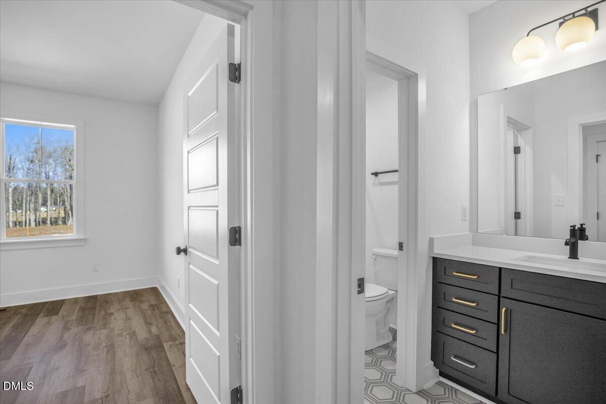 Bathroom with a dark vanity and geometric tile, opening to a separate toilet room and bedroom.