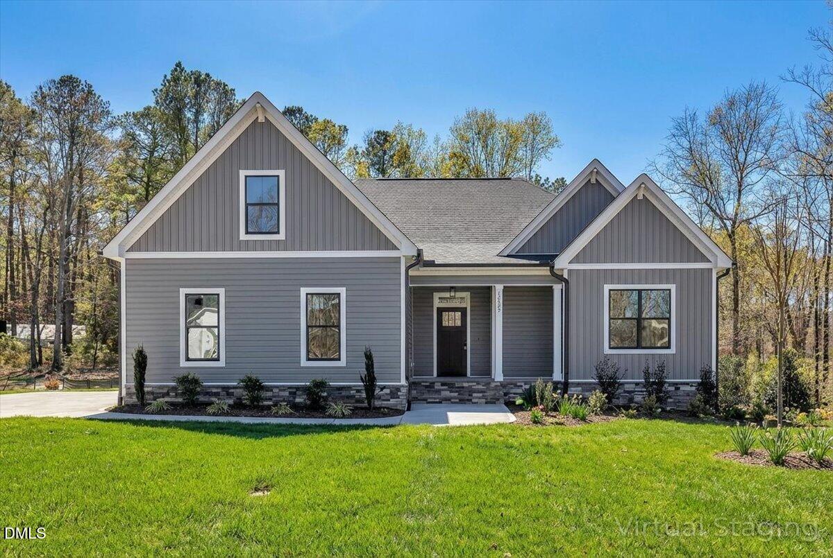 Gray house with multiple front gables, stone foundation accents, and a green lawn.