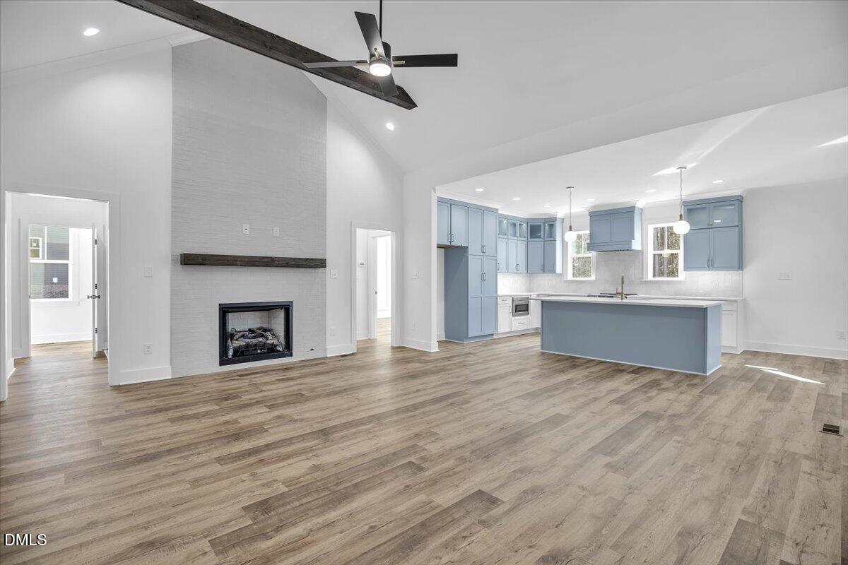 Open living room and kitchen with vaulted ceiling, fireplace, blue cabinets, and large island.