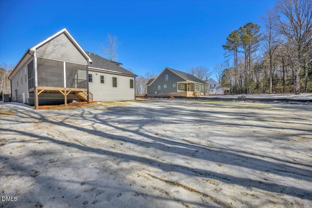 Gray house with a raised screened porch beside neighboring homes and a snow-dusted yard.
