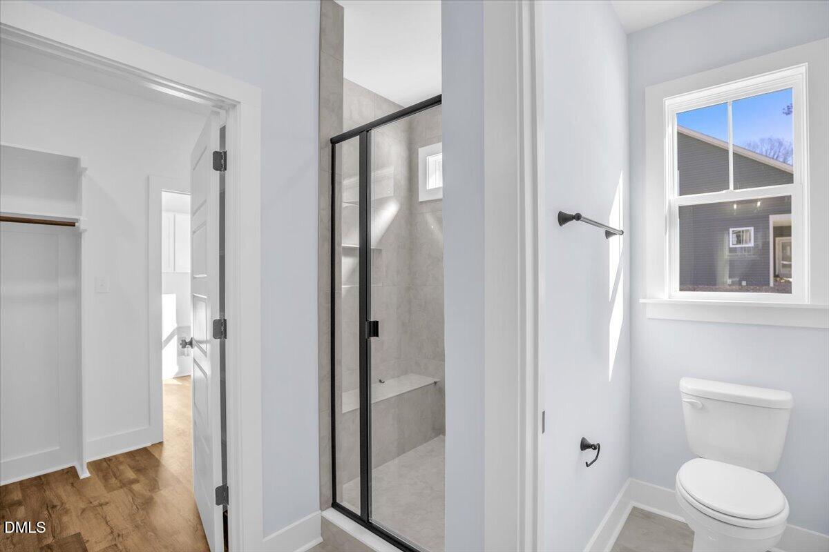 Bathroom with a black-framed glass shower and a window above the toilet.