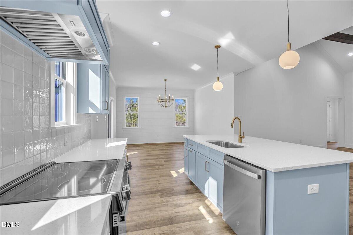 Bright kitchen with pale blue cabinets, a large white island, stainless steel appliances, and wood flooring.