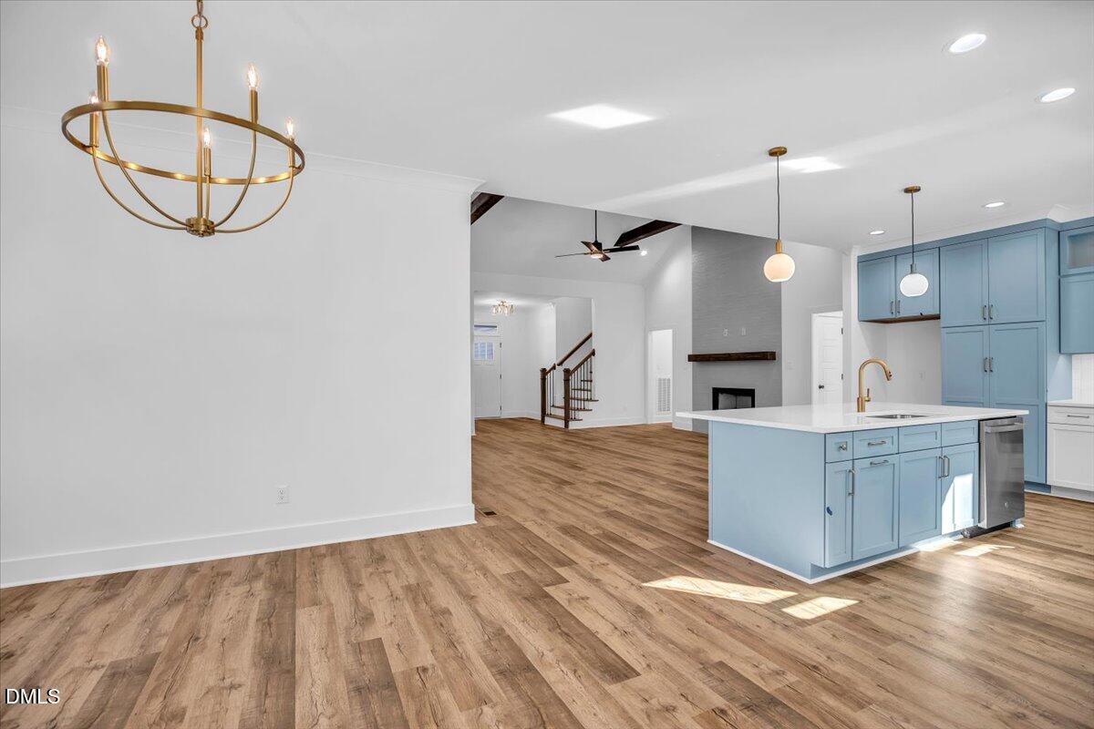 Open-plan kitchen with blue cabinets and island adjoining a living area with fireplace.