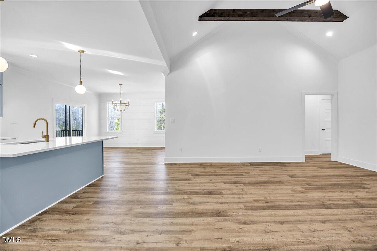Open kitchen and living area with a blue island, wood-look floors, and vaulted ceiling.