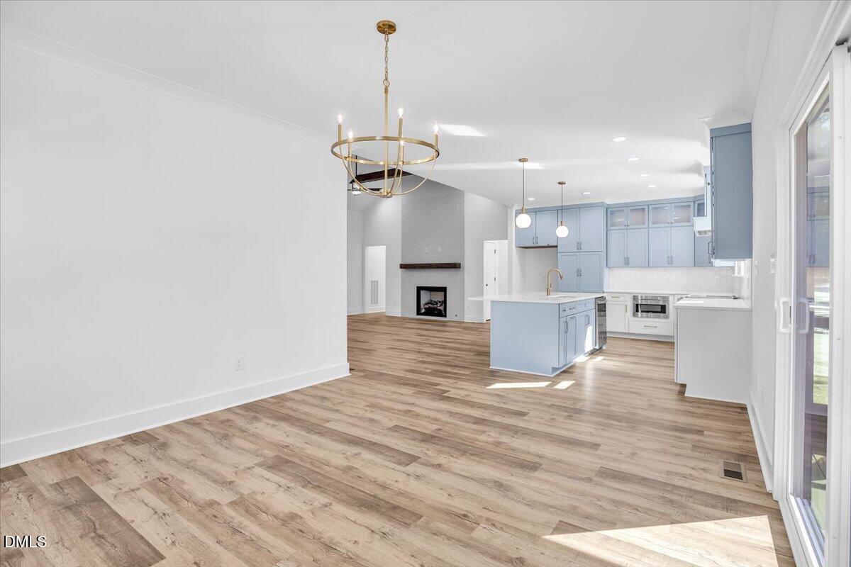 Open-plan dining area, kitchen, and living room with blue cabinets, an island, and a fireplace.