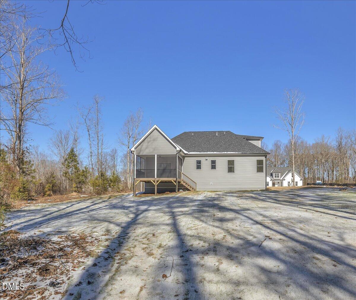 Gray-sided house with a raised screened porch and bare, snow-dusted yard.