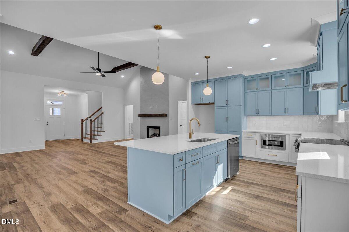 Kitchen with blue cabinetry and a large white island opening to a living area with a fireplace.