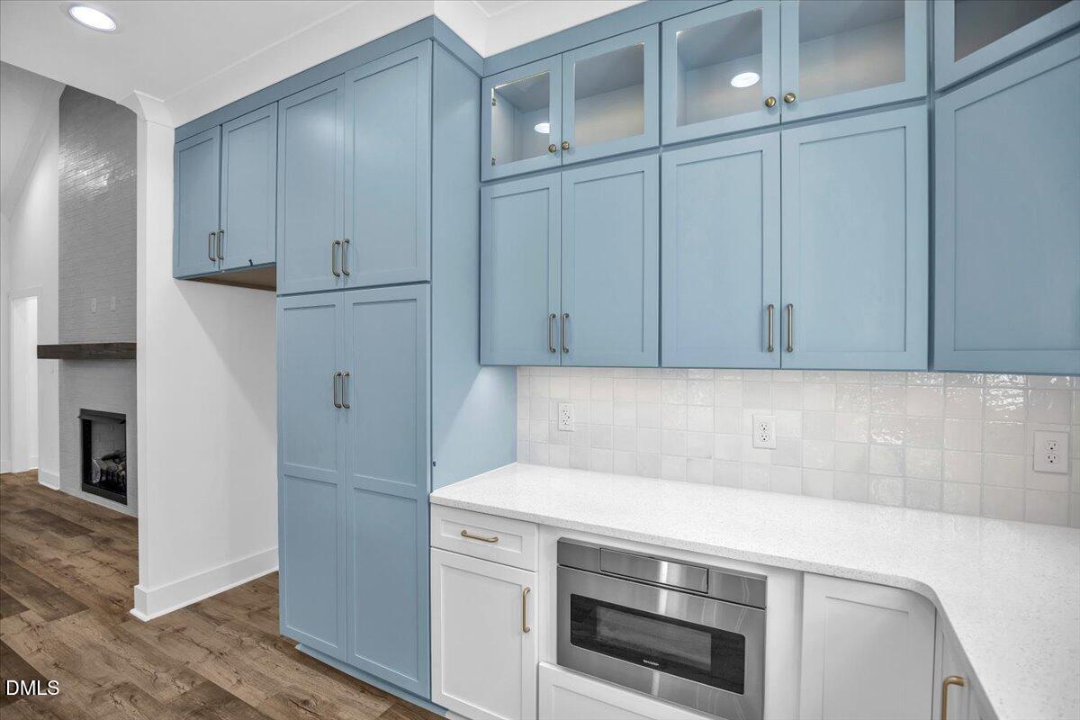 Kitchen with blue built-in cabinets, white counters, and a stainless-steel microwave.