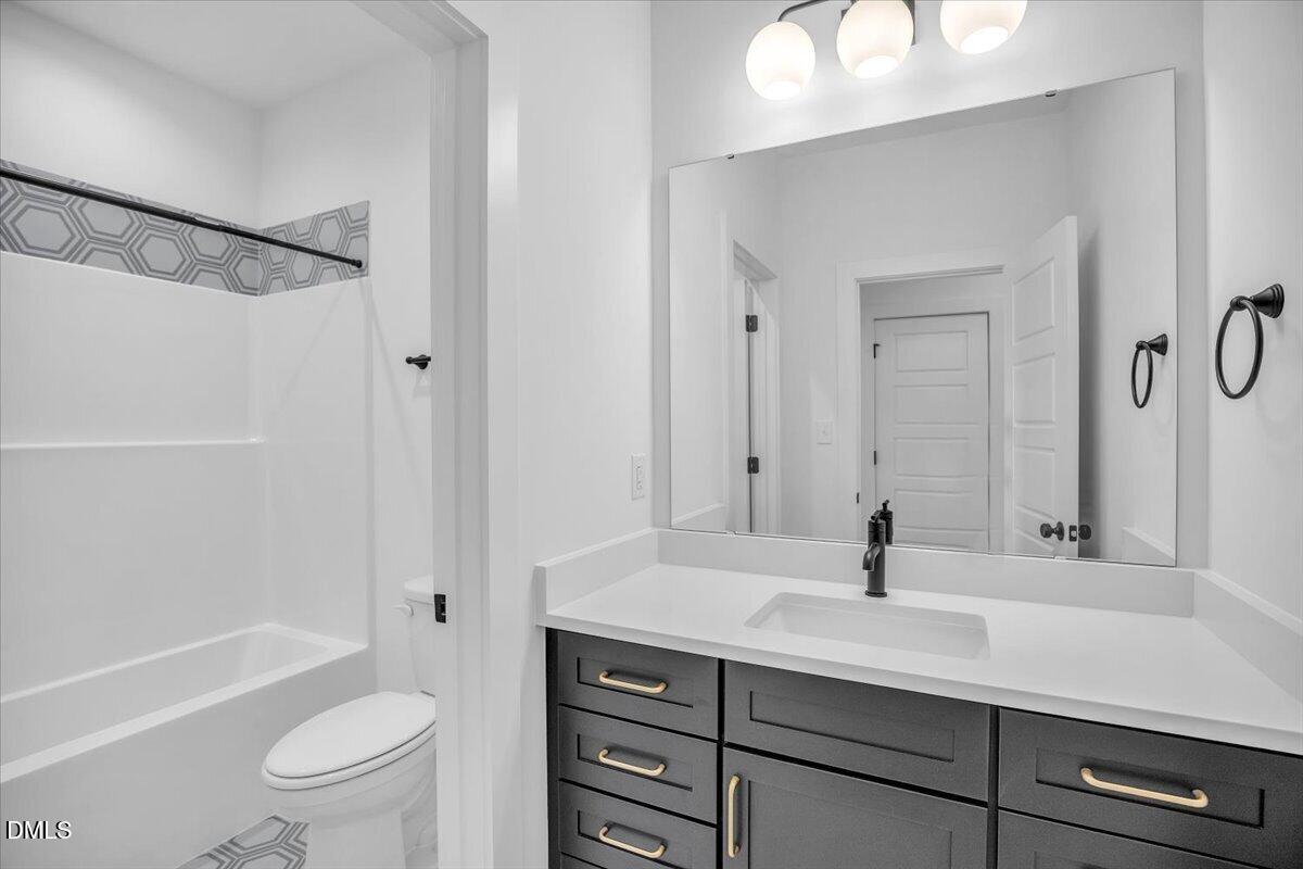 Bathroom with a dark vanity, white countertop, and bathtub with geometric accent tile.