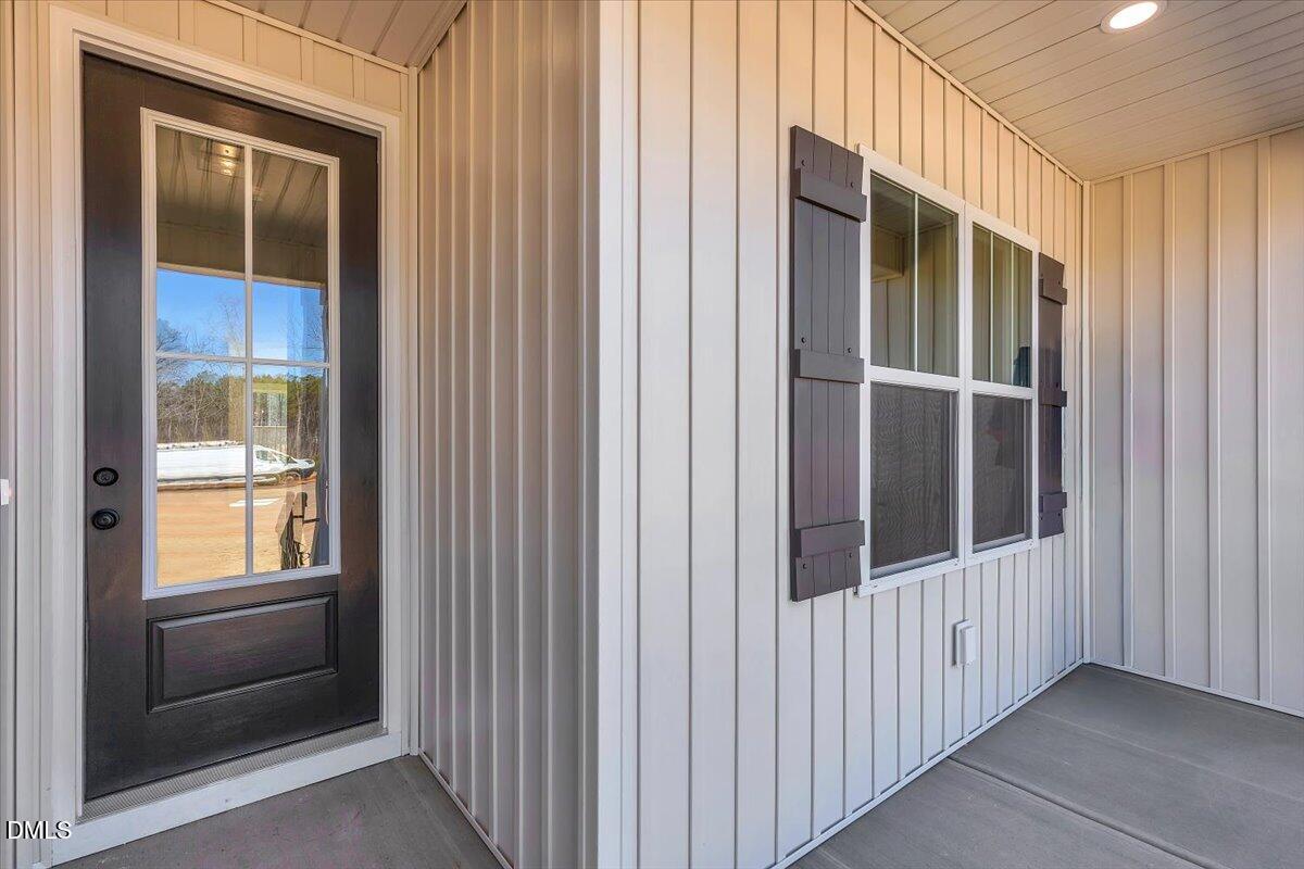 Covered front porch with a dark glass-paneled door and a shuttered window.