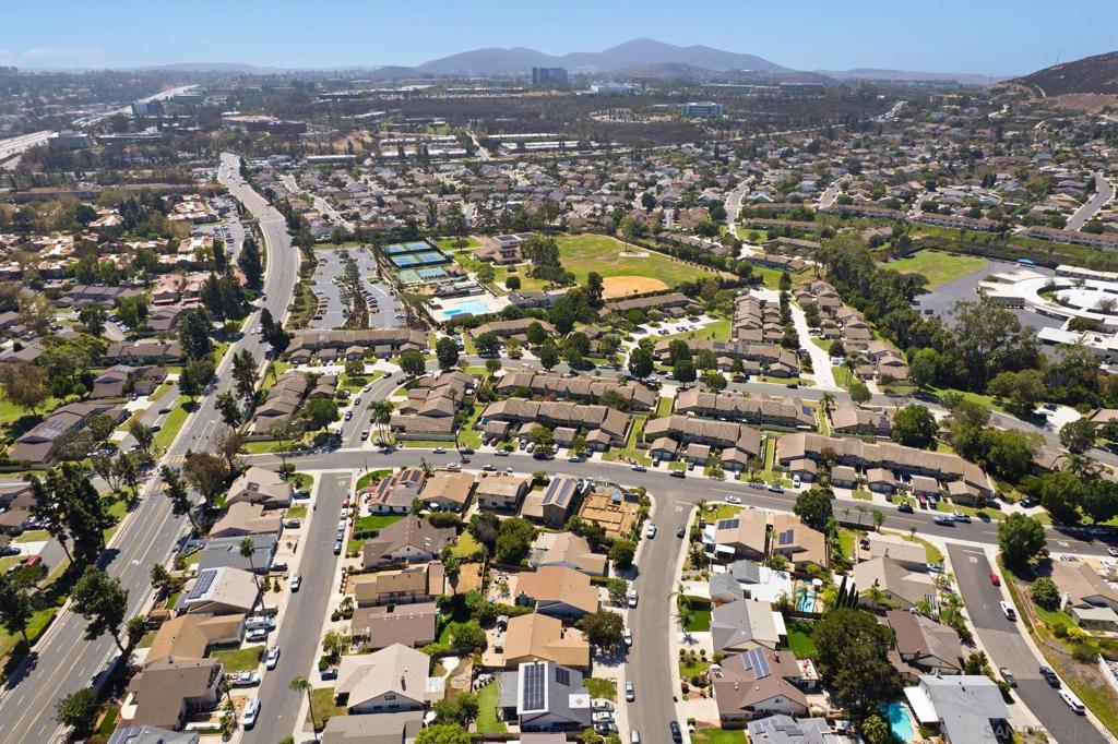 Aerial view of a San Diego neighborhood with homes, recreation facilities, and distant hills.
