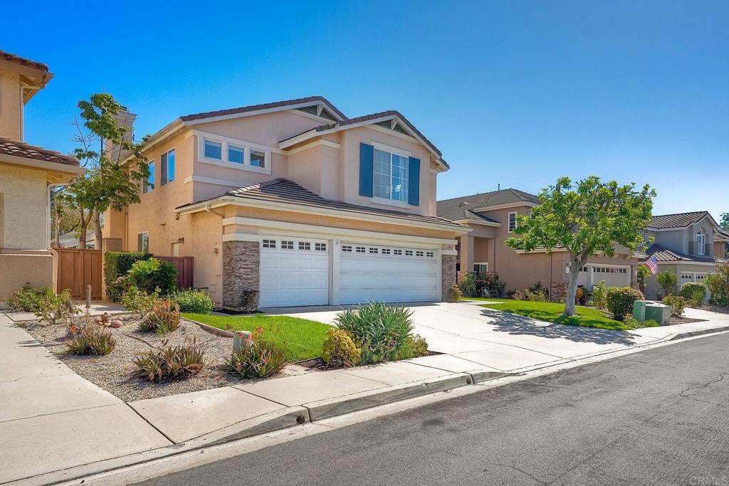 Two-story stucco home with blue shutters, double garage, and landscaped front yard.