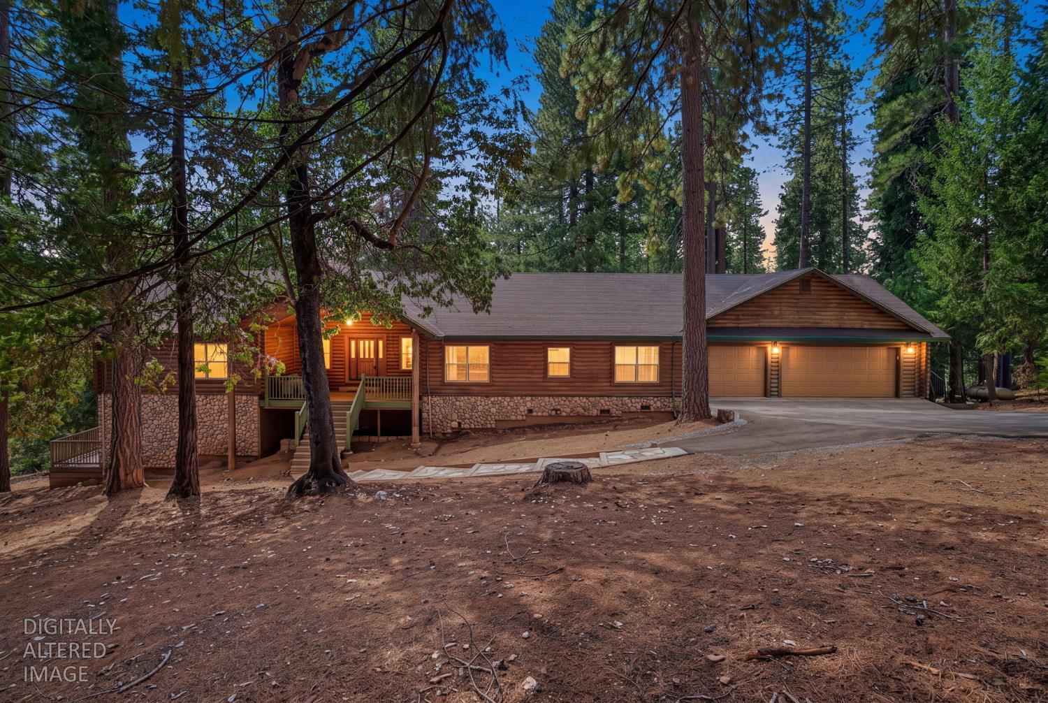 Wood-sided home with a stone foundation and two-car garage, surrounded by tall pines at dusk.