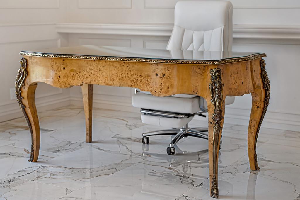 Office with an ornate wood desk, white swivel chair, and polished marble floor.