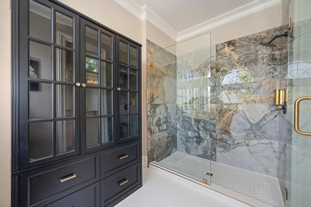Bathroom with a marble-tiled glass shower and dark built-in vanity.