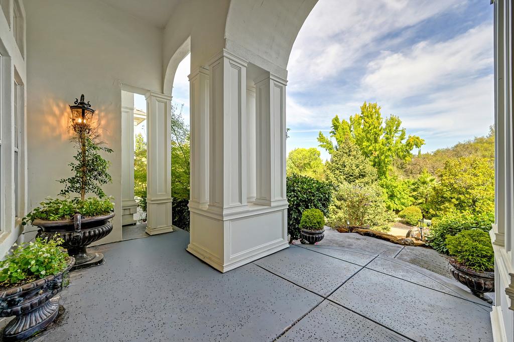 Covered porch with white columns, urn planters, and a view of the landscaped garden.