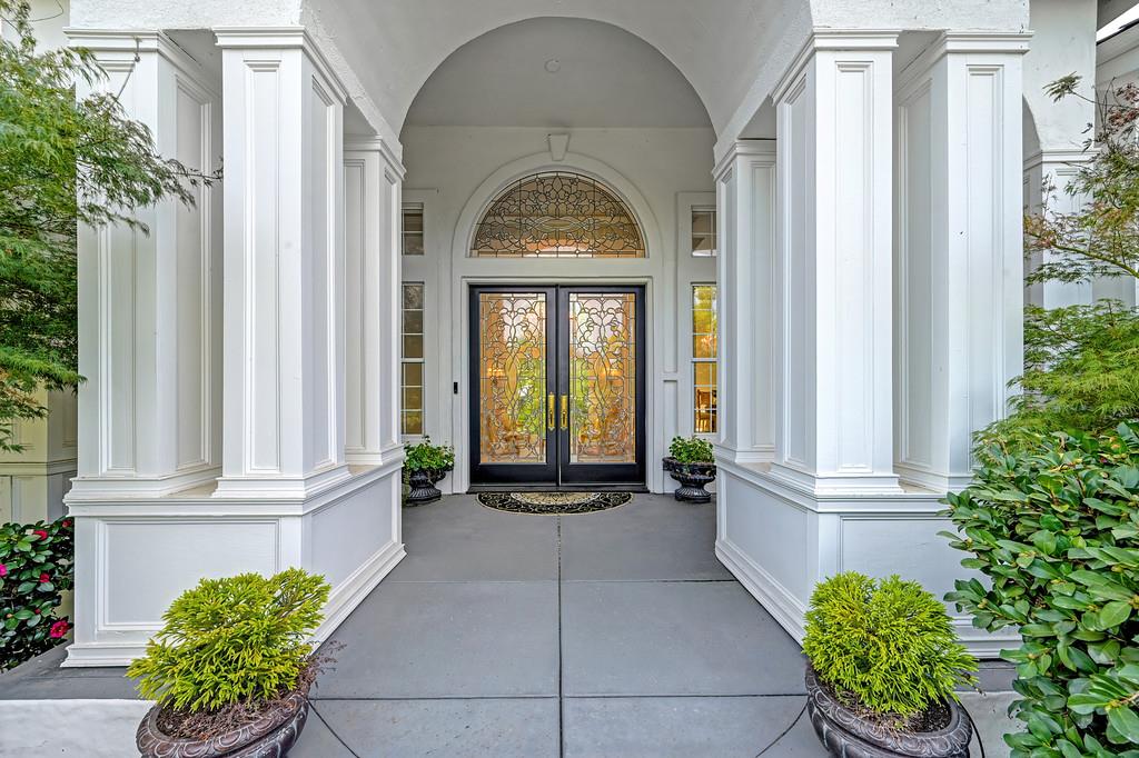 White-columned front entrance with stained-glass double doors beneath an arched portico.