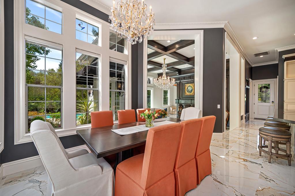 Formal dining room with coral chairs, tall windows, and a crystal chandelier.