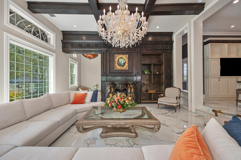 Formal living room with a crystal chandelier, dark wood fireplace, and white sectional seating.