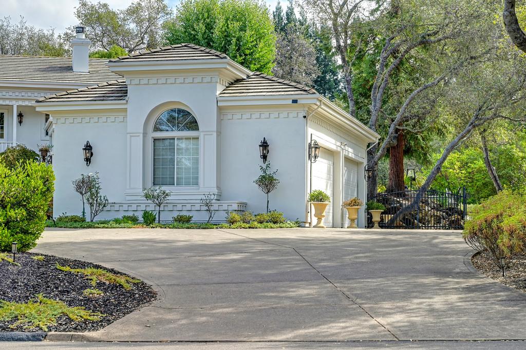 White stucco home with an arched window, tiled roof, and broad curved driveway.