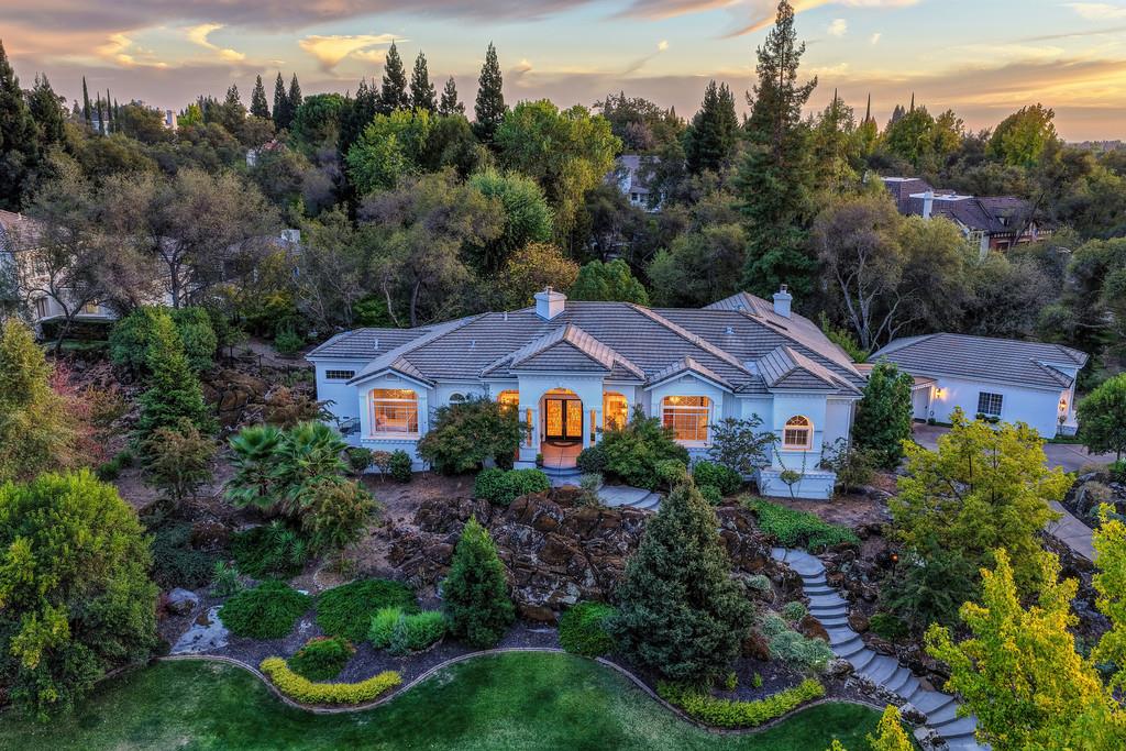 Aerial view of a single-story home with tiled roof and landscaped gardens at sunset.