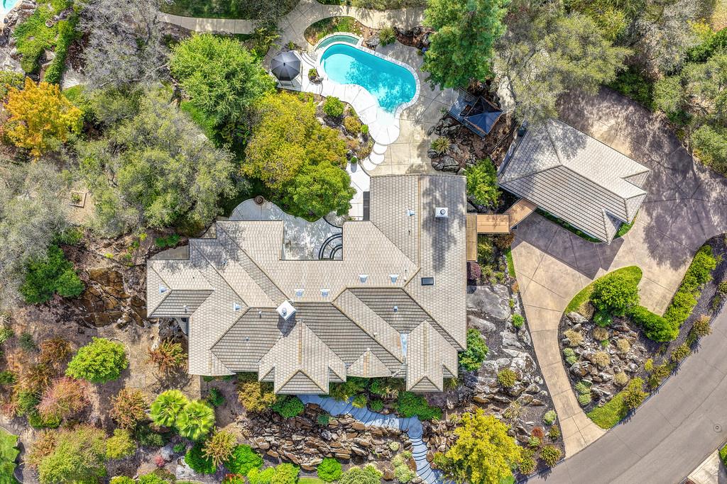 Aerial view of a tiled-roof home with a swimming pool, landscaped grounds, and curved driveway.