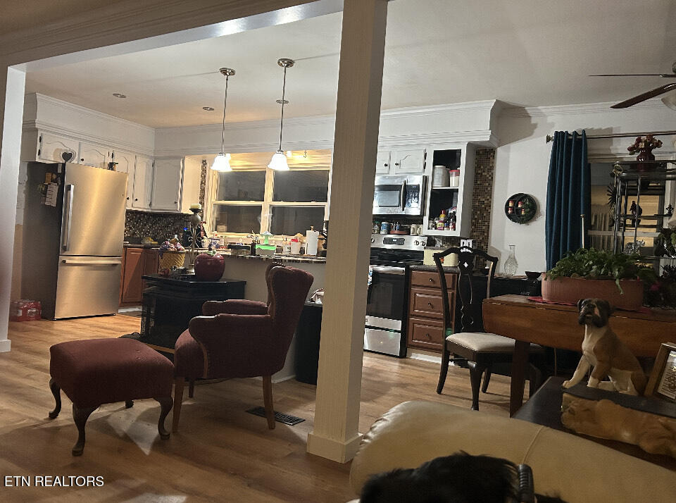 Open-plan kitchen and dining area with wood floors, pendant lights, and pets.