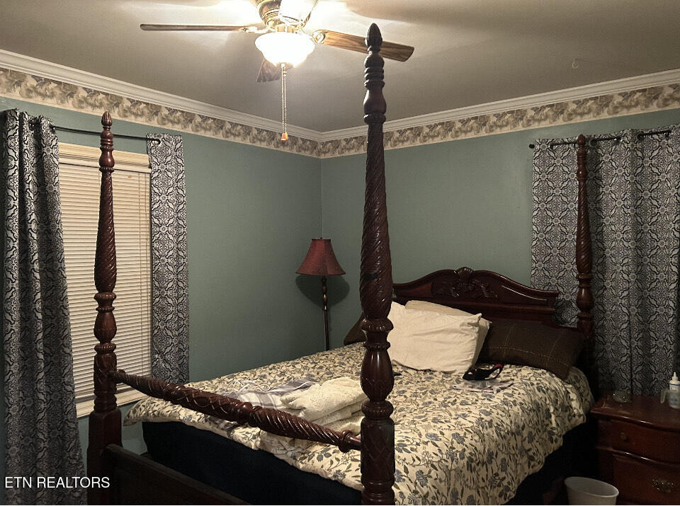 Bedroom with a dark carved four-poster bed and floral bedding.