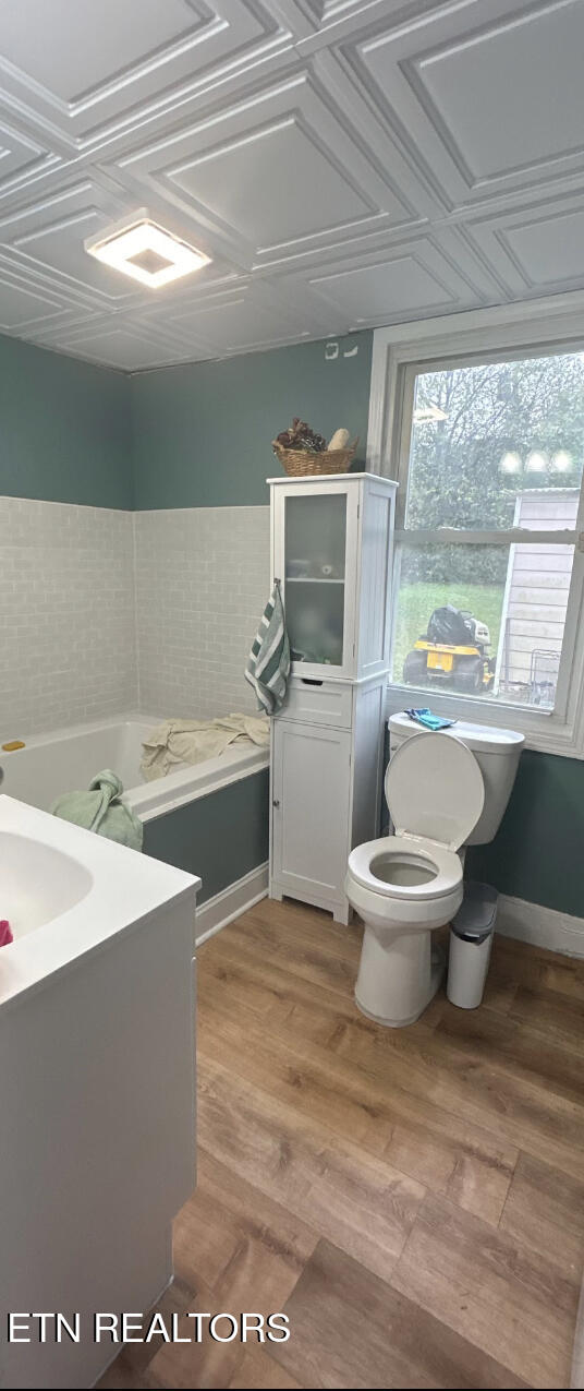 Bathroom with a bathtub, teal walls, decorative paneled ceiling, and window.