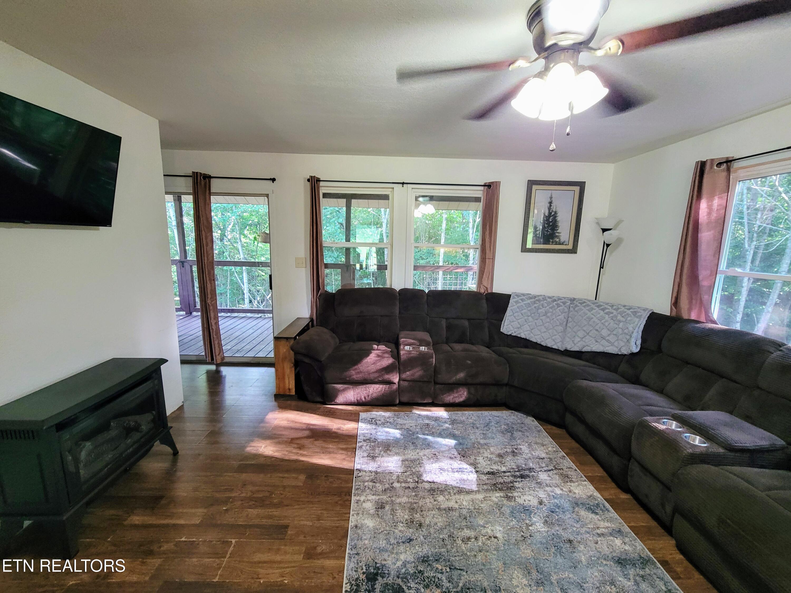 Furnished living room with a large sectional, sliding glass door, and wooded views.