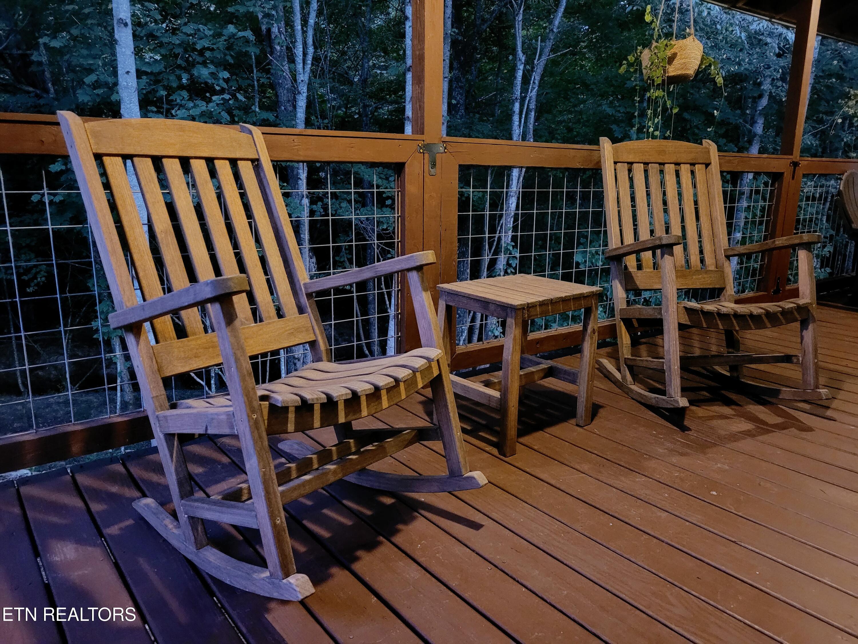 Wooden deck with two rocking chairs overlooking dense woods.