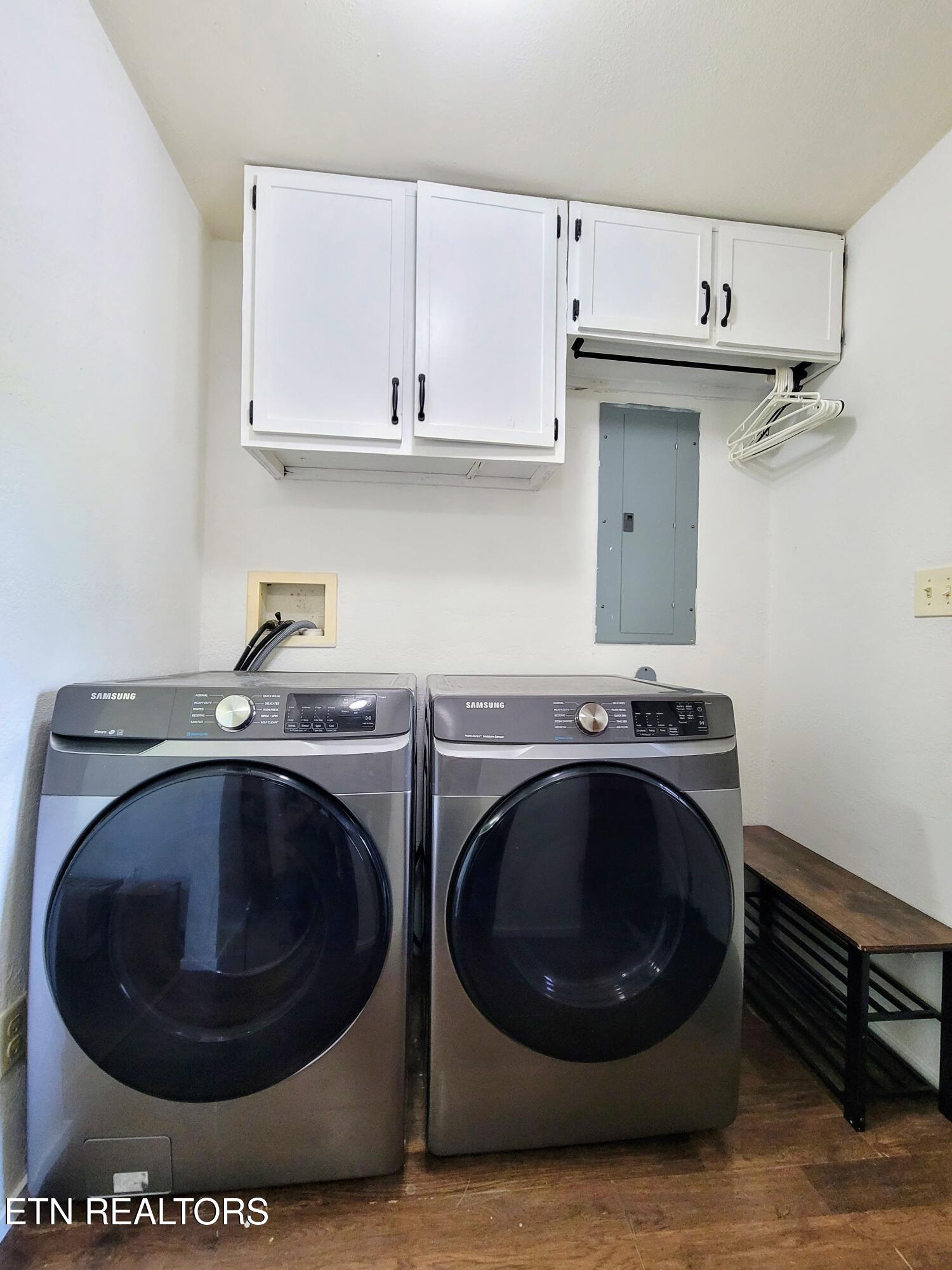 Laundry room with matching front-loading washer and dryer beneath white cabinets.
