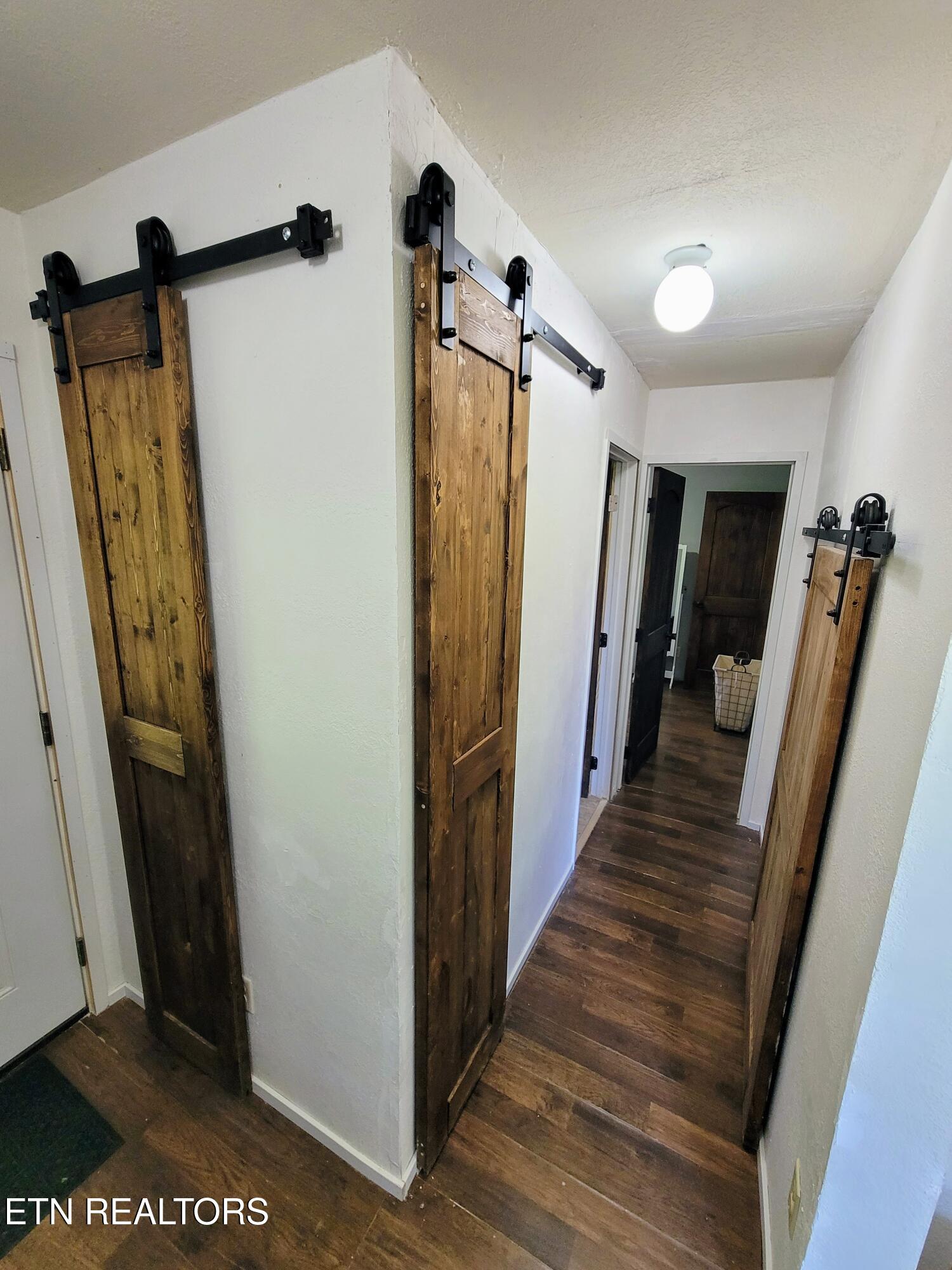 Hallway with dark wood floors and rustic sliding barn doors.