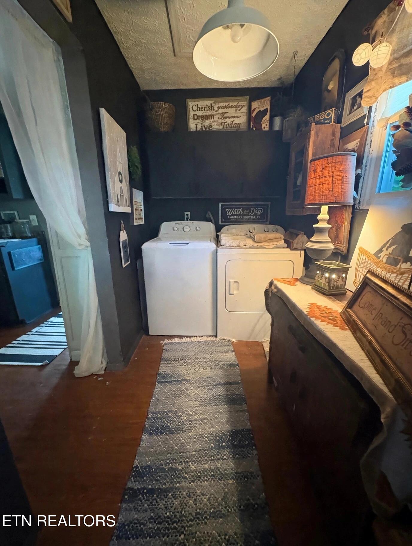 Laundry room with a white washer and dryer, patterned rugs, and vintage-style decor.