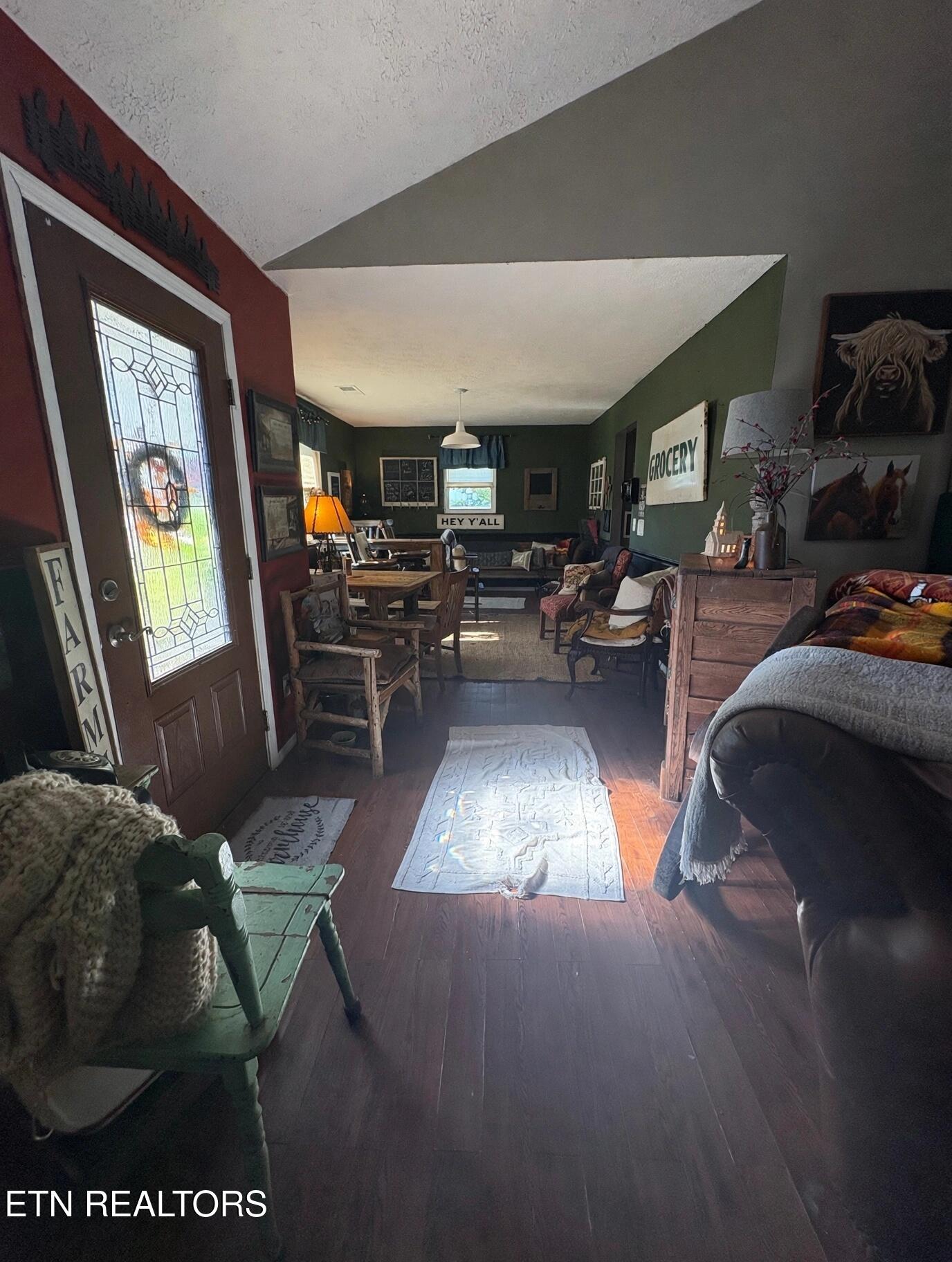 Furnished living and dining room with a glass-panel entry door, rustic decor, and dark wood floors.